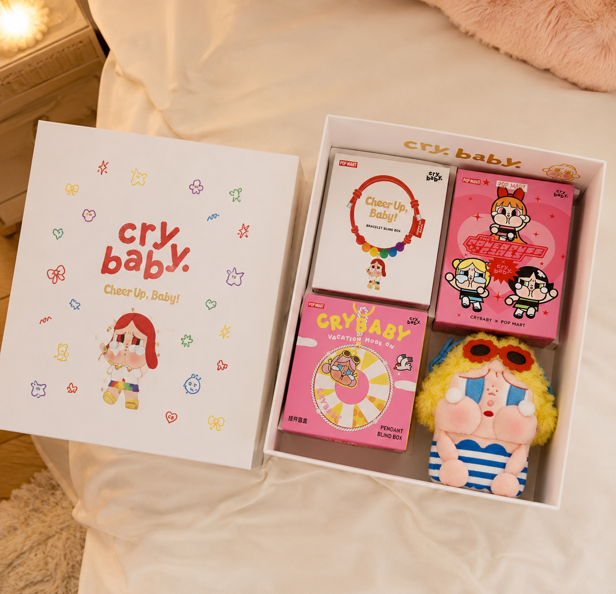 POP MART CRYBABY Soft Hearts boxed set in pink and white packaging, displayed on a soft beige bed.